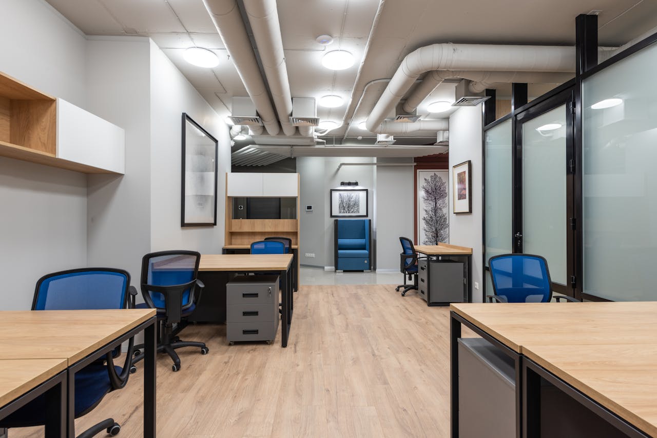 Bright and spacious modern office workspace featuring wooden desks and blue chairs.
